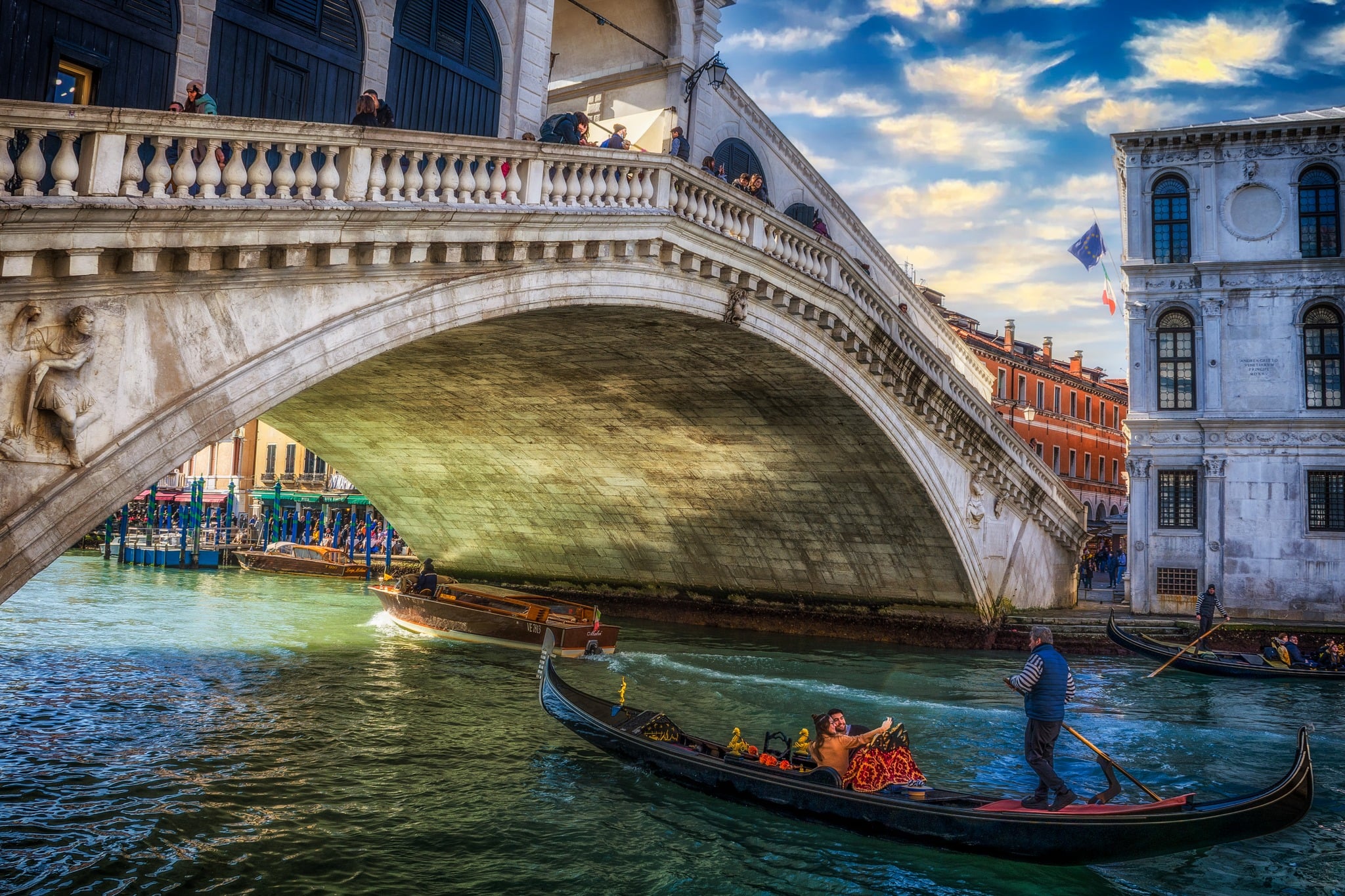 Venezia, prospettiva triangolare tra ponte, barche e facciata in luce dorata del tardo pomeriggio
