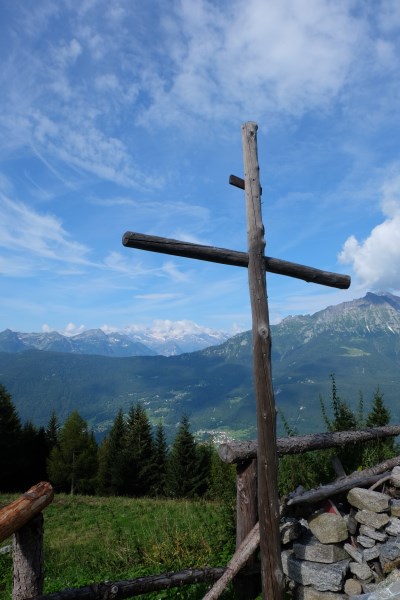 Croce in primo piano e orizzonti montani: lettura di una chiesetta alpina