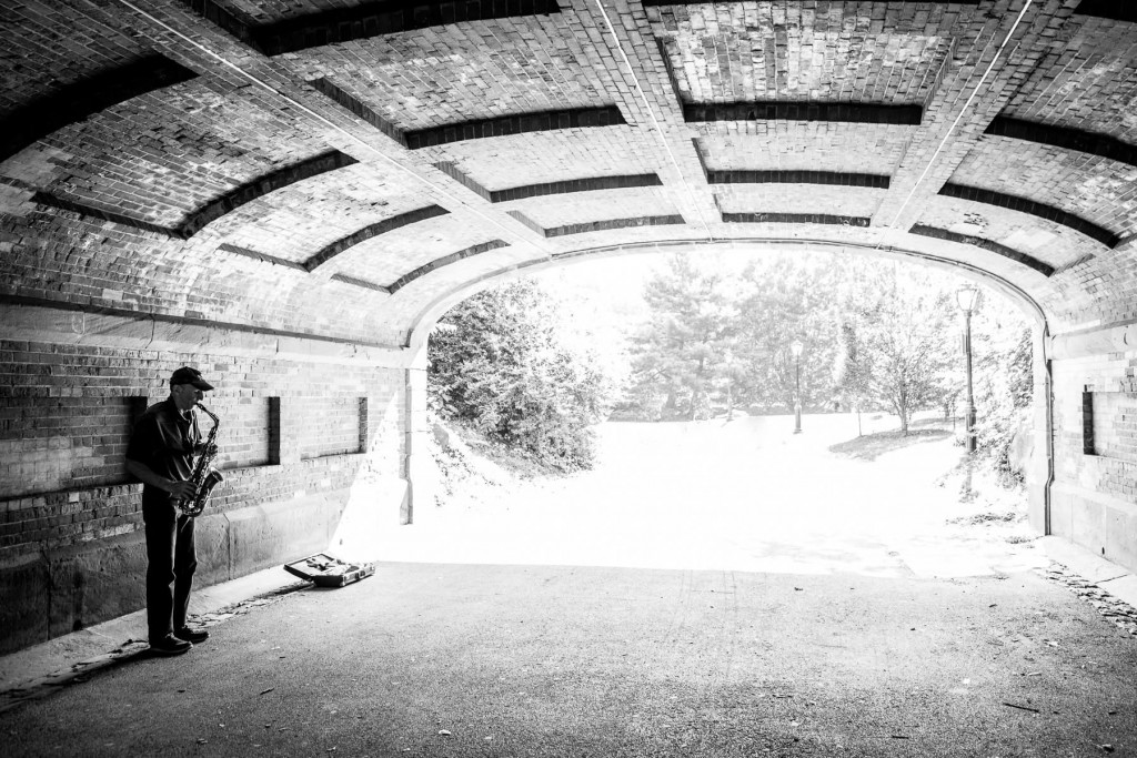 Sassofonista in controluce: quiete urbana tra tunnel e luce