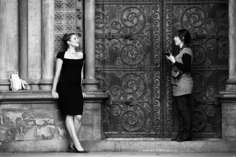 Dietro la fotocamera: dialogo tra modello in nero e portone decorato in bianco e nero