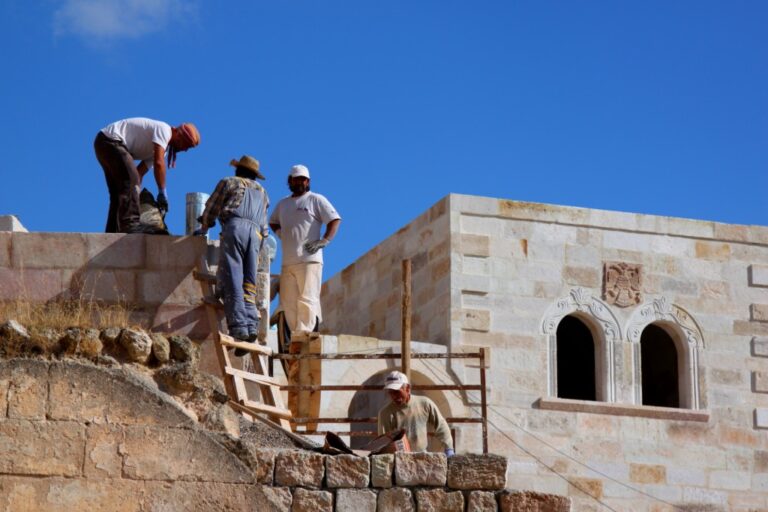 Coordinazione e luce: lavori di cantiere e pietra in profilo contro il cielo azzurro