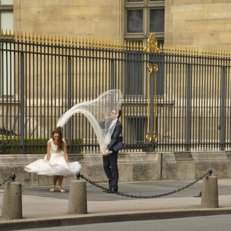 Velo in danza tra la cancellata dorata: intimità urbana in un inizio pubblico