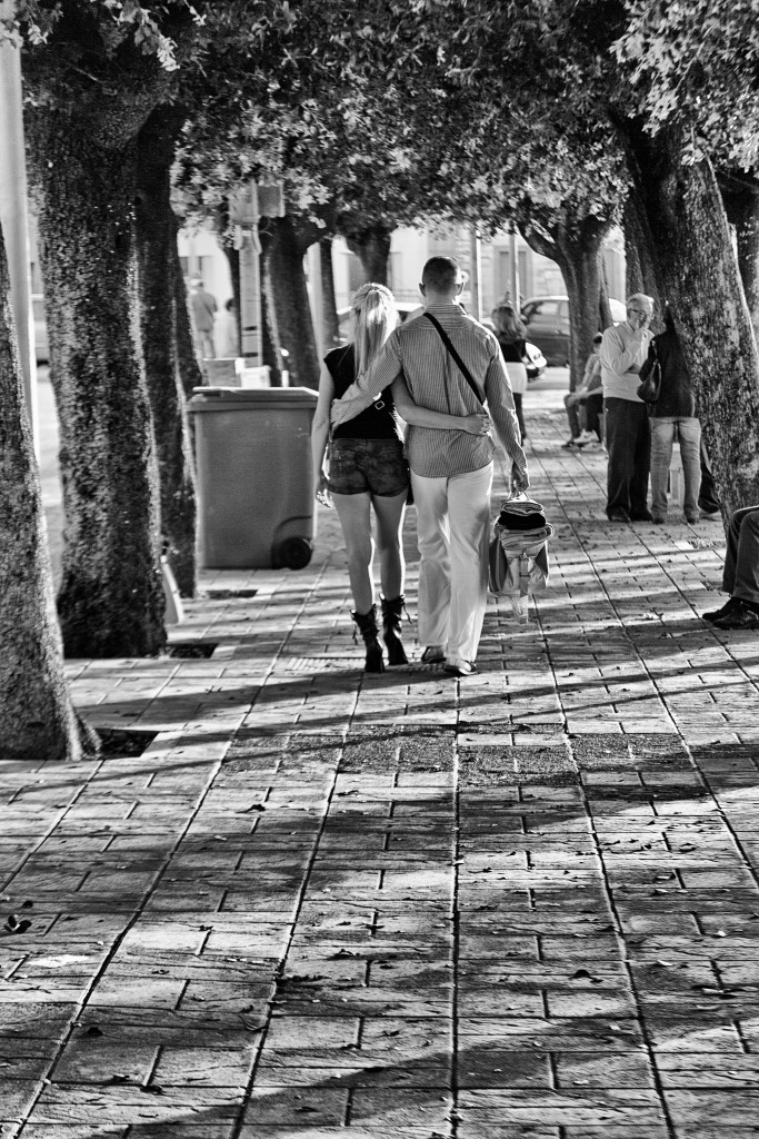 Intimità sospesa lungo il viale: bianco e nero e superfici in rovina rivelano una quotidianità ferma nel tempo