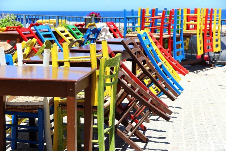 Preparativi all’aperto: ritmo di sedie, colore e mare all’orizzonte