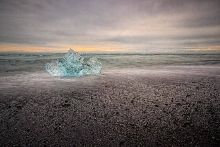 Ghiaccio e sabbia scura: quiete luminosamente contrastata all’alba sul fronte dell’oceano glaciale