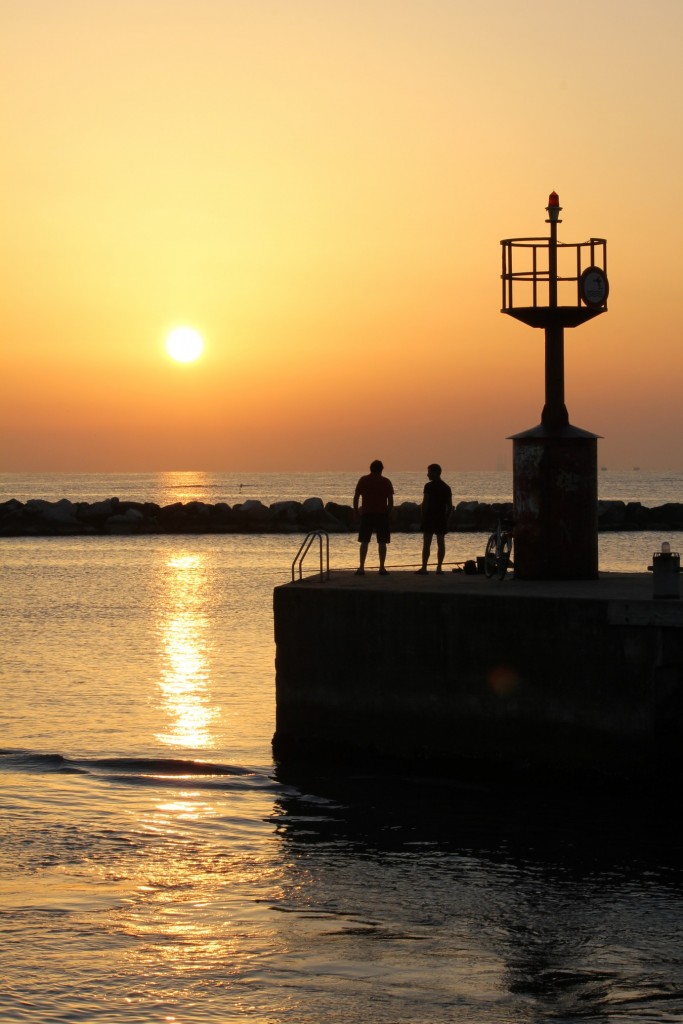 Silhouette estive: calore dolce, linee guidate e profondità tra molo e sole al tramonto