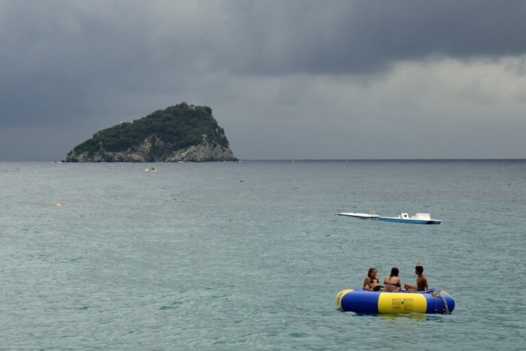 Quieta precarietà: gommone, mare e nuvole in controluce estivo