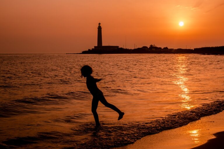 In bilico tra luce dorata, silhouette ferma e mare increspato sul ponticello