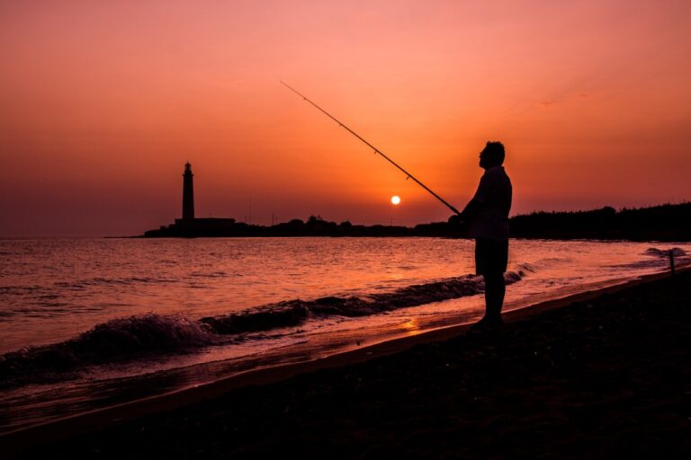 Speranza al tramonto: silhuette, vela e faro in equilibrio cromatico