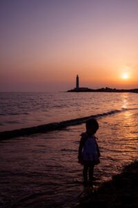 Tramonto al faro: siluette, riflessi e quiete marina a foto finita in luce crepuscolare
