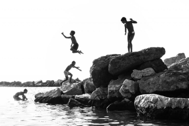 Tuffi e fiducia in bianco e nero: dinamismo tra rocce e onde