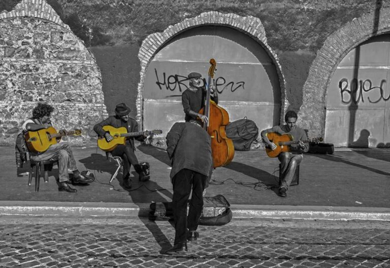 Roma di strada: contrabbasso al centro, luce, gesti e complicità tra musicisti urbano