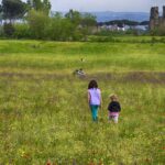 Domenica in campo: profondità, colori naturali e ritmo tra bambini e rovine