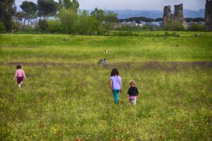 Domenica in campo: profondità, colori naturali e ritmo tra bambini e rovine