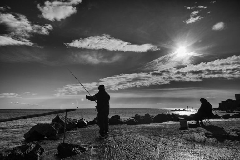 Tramonto in controluce: conversazione tra due approcci di pesca e silhouette in bianco e nero